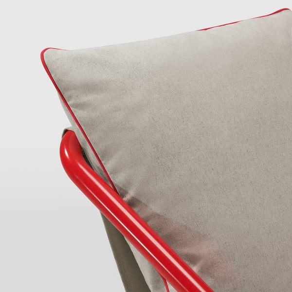 A modern armchair with soft cushions, featuring a shiny red metal frame and neutral-toned cushions with red piping, offering comfort and style.