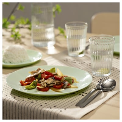Green glass plate with food, crystal glasses, silverware on striped placemat.