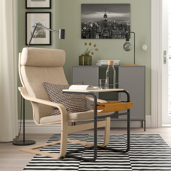 Modern home office with an OLSERÖD beige chair, wooden desk, striped rug, and nyc art. Sleek, functional setup with stylish decor.