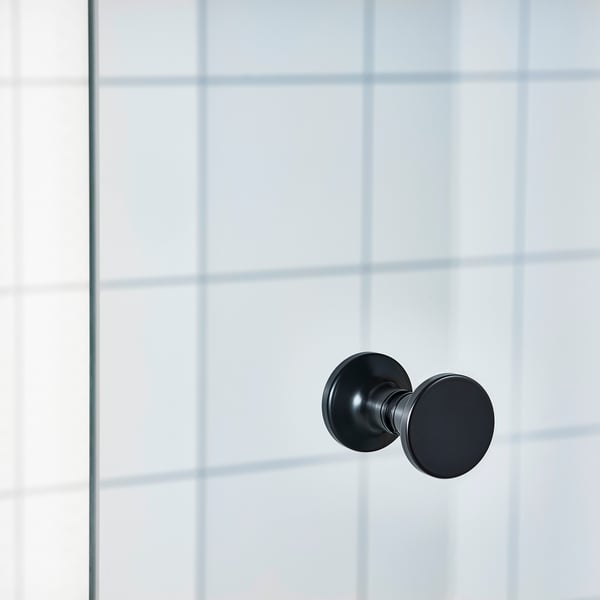 Modern black door handle mounted on clear glass wall panel. Sleek design for contemporary shower enclosure.