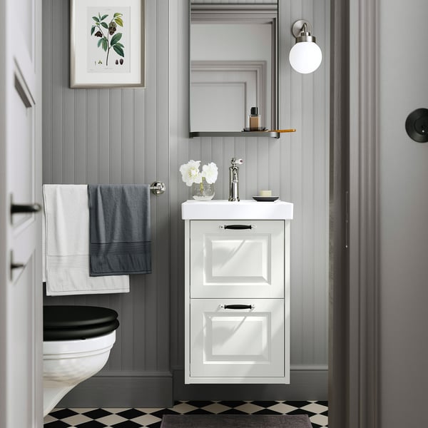 Modern bathroom with ORRSJÖN washbasin, grey walls, chequered floor, small mirror, dark hardware, and hanging towels.