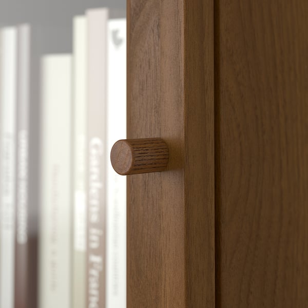 A wooden door with a cylindrical handle and a bookcase in the background.