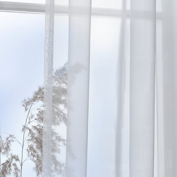 Sheer white curtains with subtle pattern gently diffuse daylight, creating privacy while maintaining a serene, minimalist look.