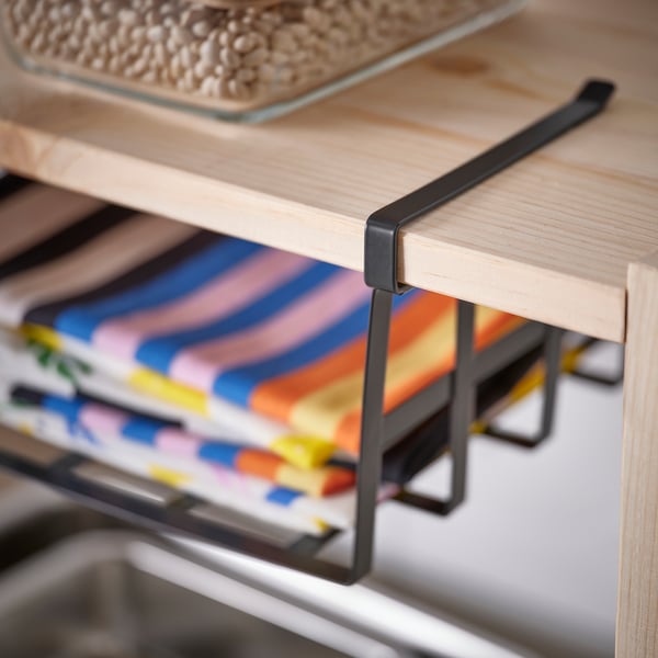 Wooden shelf with a metal clip-on basket, holding colourful kitchen items.