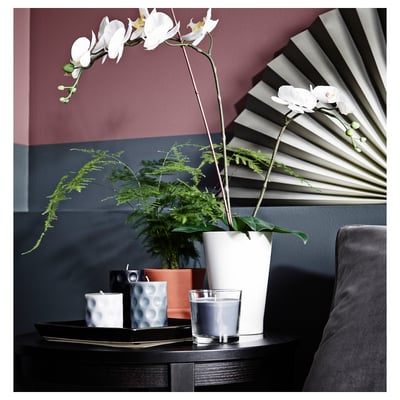 Modern living room with orchid, fern, candles, and wall fan.