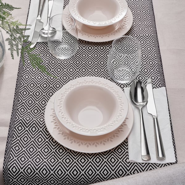 Table setting with PARADISISK tempered glass bowls and plates, silverware, napkins, and glasses on geometric placemat.