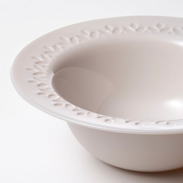 Shallow light pink bowl with a textured rim on a white surface.