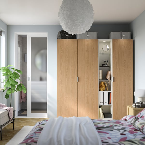 Modern bedroom with tall light oak PAX wardrobe, stylish accessories.