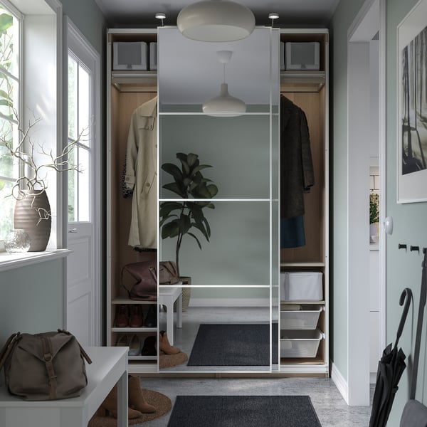 Modern entryway with open closet featuring mirrored doors, green painted interior, hanging coats, hanging plant, and bench.