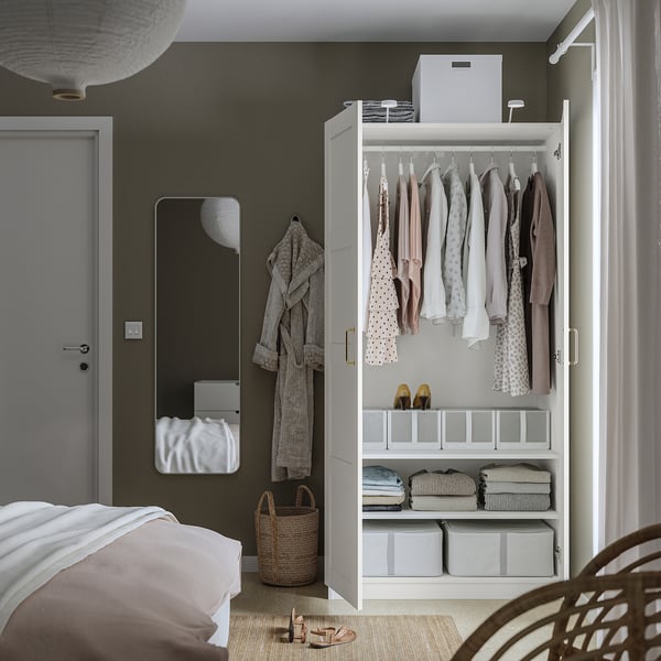 Minimalist bedroom with open wardrobe, mirror, bed, rug, basket