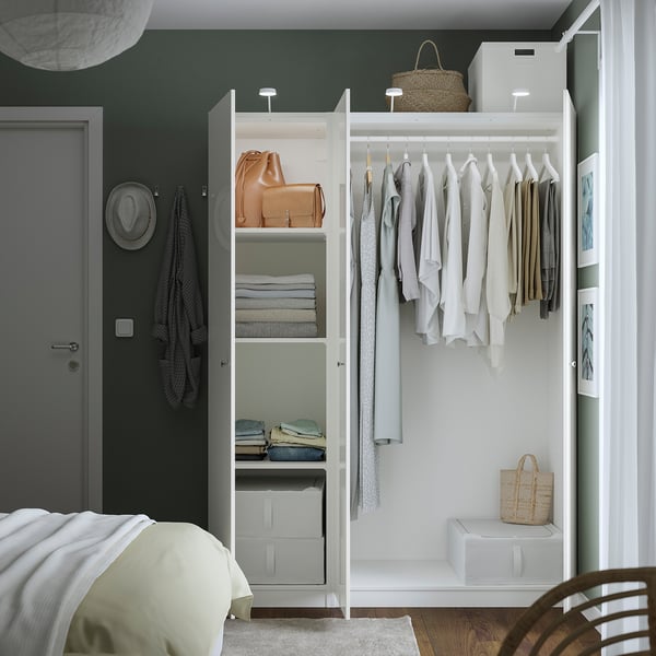 Modern bedroom with white PAX wardrobe. It organises clothes on hangers, has shelves for folded clothes, and uses space efficiently.
