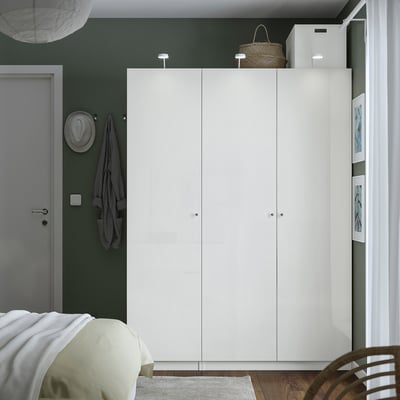 White PAX wardrobe in bedroom, three-section with soft-close hinges, adjustable feet, baskets and a hat on top.