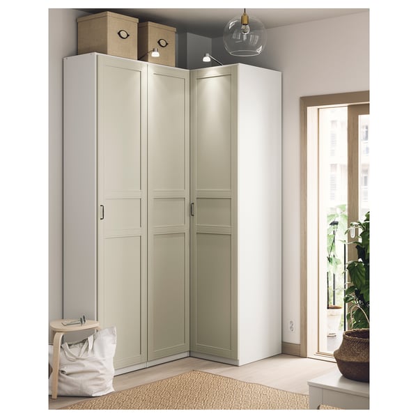 Modern corner wardrobe in beige and white, with light fixtures, showcasing minimalist design.