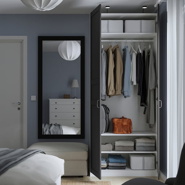 Bedroom with open wardrobe displaying clothes, bags, and folded wear on shelves, reflecting organised storage solutions.
