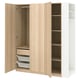 A light brown wood PAX wardrobe with open doors, revealing storage shelves and drawers. It has a simple, practical design.