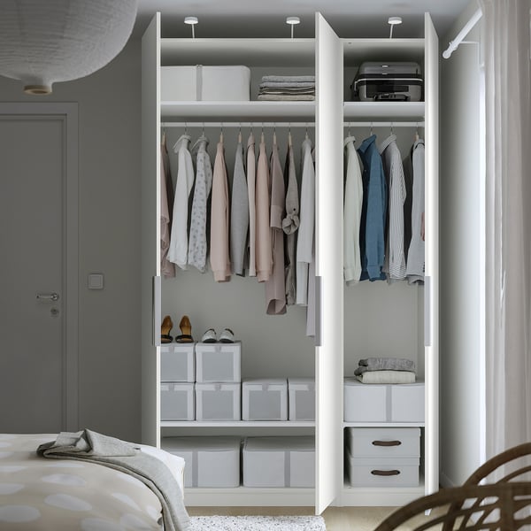 A well-organized white wardrobe with clothes and storage boxes, featuring adjustable feet, and integrated lighting.