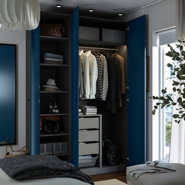 Open wardrobe with clothes hangers, folded towels, bags, and drawers, showing organised storage solutions.