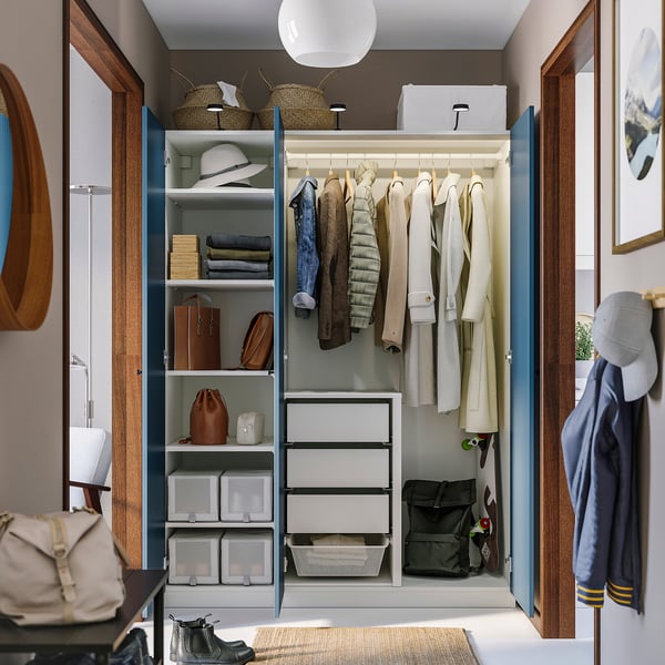 Organised closet with hanging coats, shelves, drawers, and bins, lit inside.