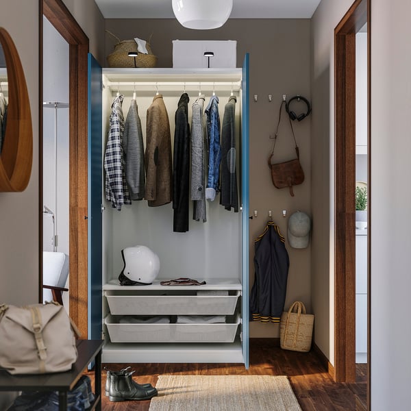 Open wardrobe displaying clothes and accessories, with closed drawers below.