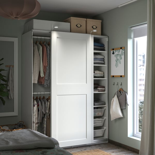 Neat nursery closet with white sliding doors and shelves storing clothes and foldables, organised in mesh baskets.