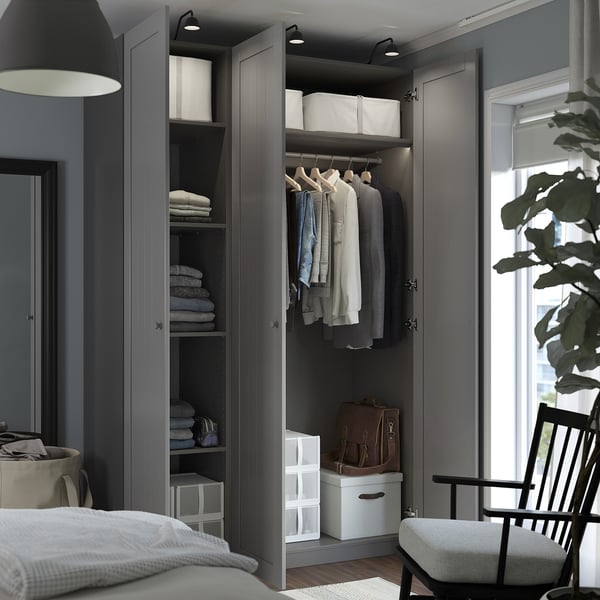 Open wardrobe with clothes, folded towels, and storage boxes in a modern bedroom.