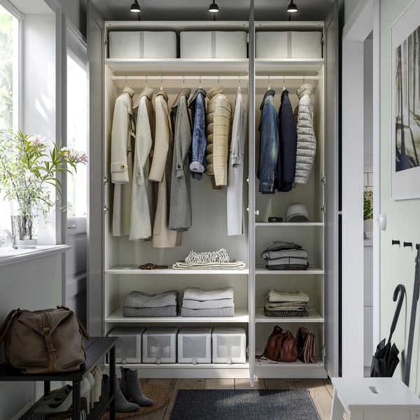 A well-organized wardrobe with hanging jackets, folded clothes, and clear storage boxes. Hinged doors and lights inside.