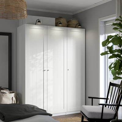 Modern bedroom with large white PAX wardrobe by window, flanked by a black rocking chair and bed.
