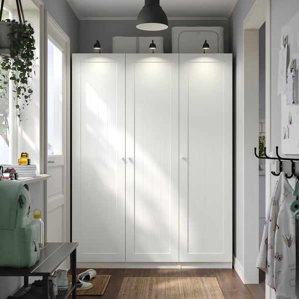 A PAX wardrobe in white, tall, with four doors. Its the main furniture, standing between windows and a desk. .