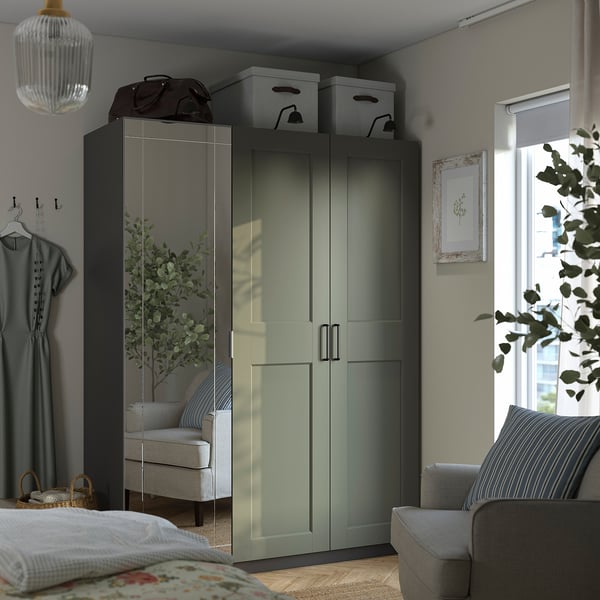 Modern bedroom with PAX wardrobe - dark & mirror doors, gray-green. Tall, fits neatly, mirrored doors reflect room, includes storage boxes on top.