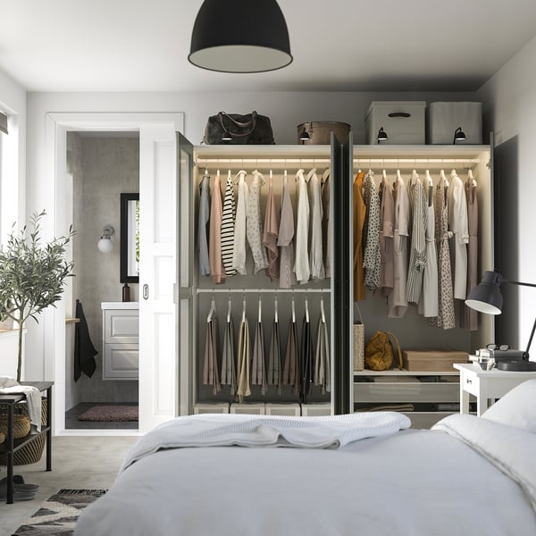Bedroom showing PAX wardrobe with sliding glass doors displaying clothes and accessories. Includes hanging space, shelves, and storage boxes on top.