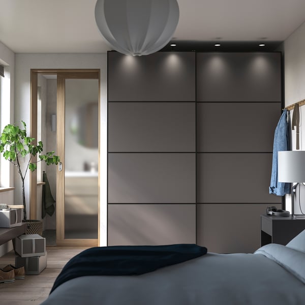Modern bedroom with grey PAX wardrobe, sliding doors, and integrated lighting.