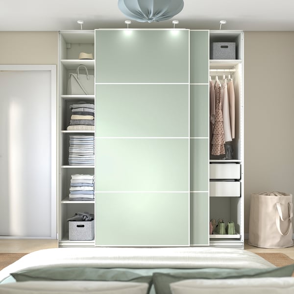 Modern bedroom with mint-green PAX wardrobe displaying clothes and storage.