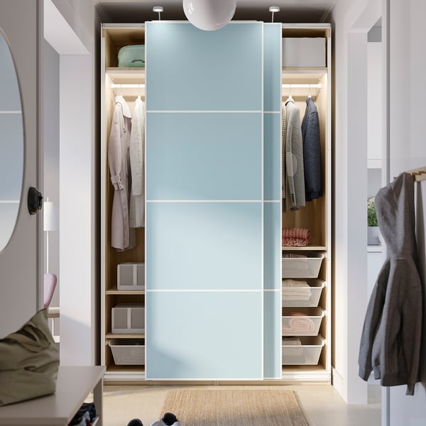 A light-filled wardrobe with sliding doors revealing organised clothes and baskets.