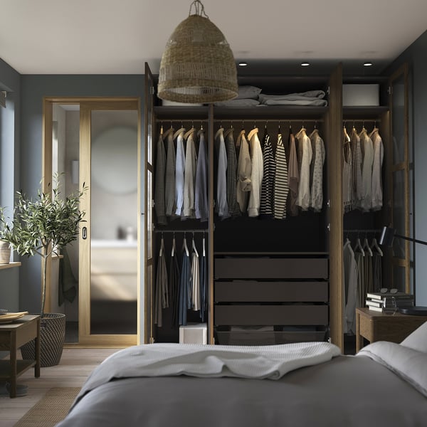 Modern bedroom with PAX wardrobe displaying clothes, drawers, and a hanging light fixture.