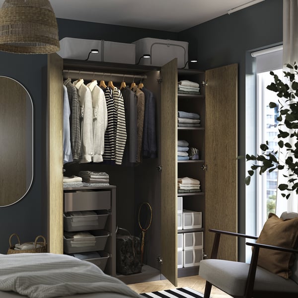 Modern wardrobe with hanging shirts, folded clothes, storage boxes, and built-in lighting.