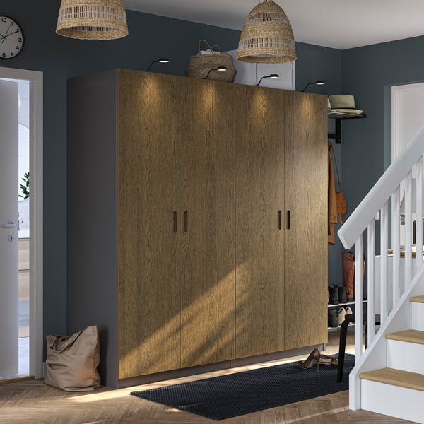 Large wooden PAX wardrobe in room, with grey walls and white staircase, topped with woven baskets and stylish lights.
