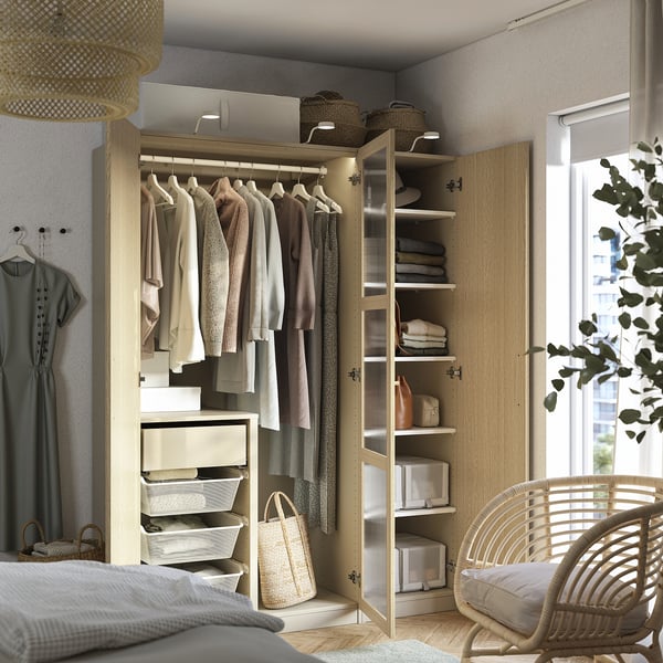 Open closet displaying clothes, lit by integrated lights. Shelves hold folded items and baskets.
