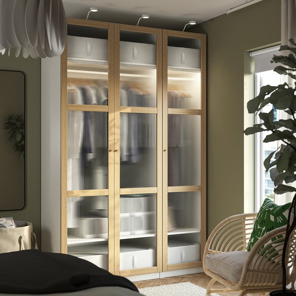 Large wooden PAX wardrobe with glass doors, surrounded by various furniture.