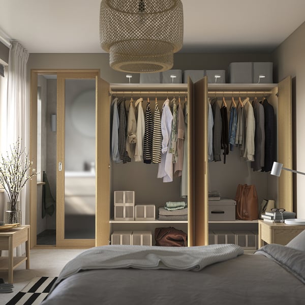Open wardrobe displaying clothes, bags, and storage boxes inside a modern bedroom.