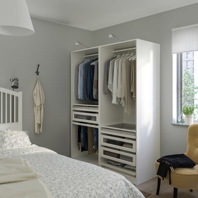 A minimalist bedroom with a white PAX wardrobe, taller than the bed and desk, holding clothes and accessories.