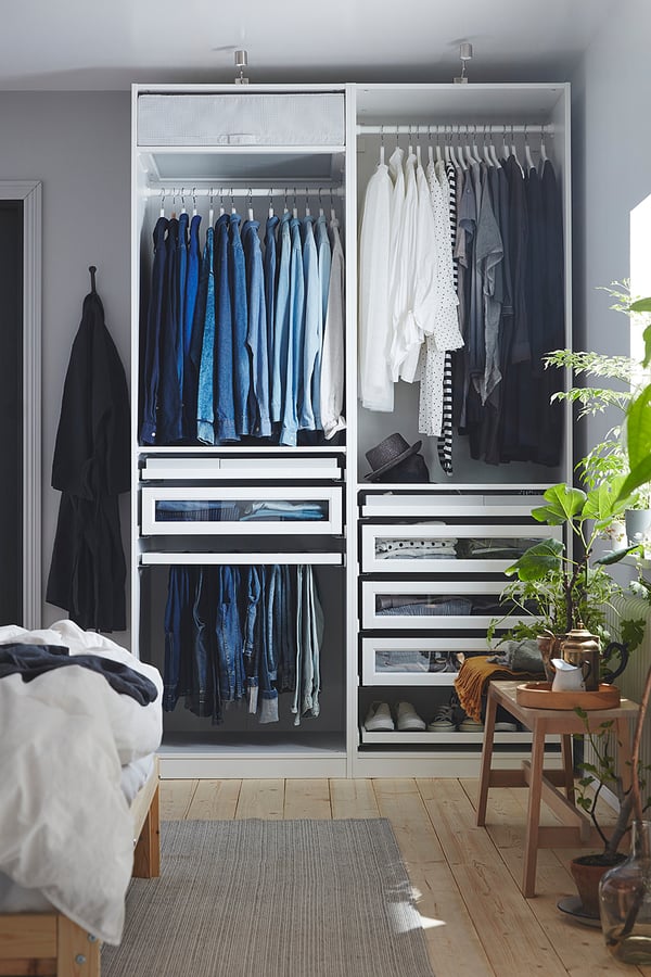 Bedroom with white wardrobe, grey rug, plants, wooden floor.