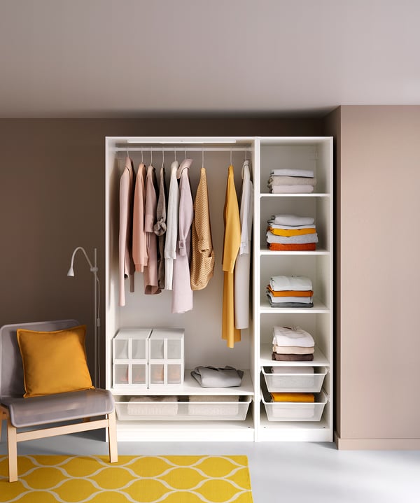 Modern closet with clothes and folded textiles, white design, yellow accents, and chair with yellow pillow.