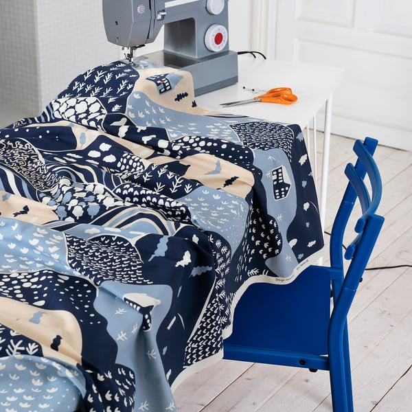 Blue patterned fabric on table, sewing machine, scissors, and chair.