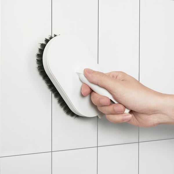 Cleaning white tiled wall with PEPPRIG brush.