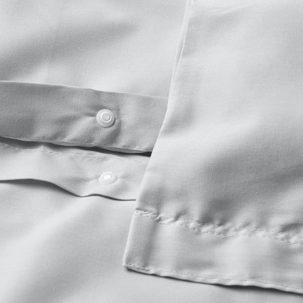 Close-up of white duvet with visible button closure, smooth fabric texture.