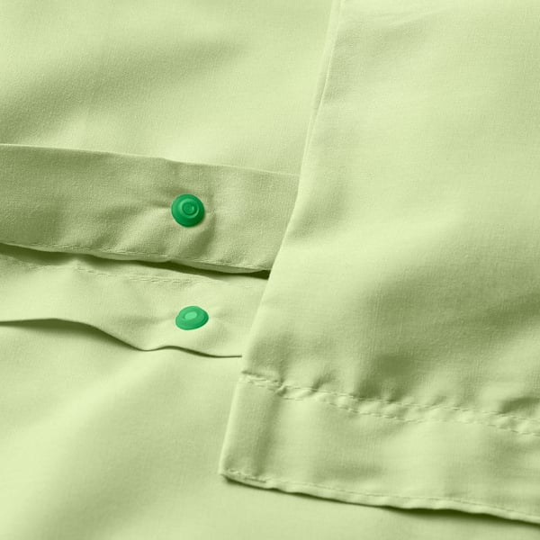Close-up of green duvet with visible pop-button closure.