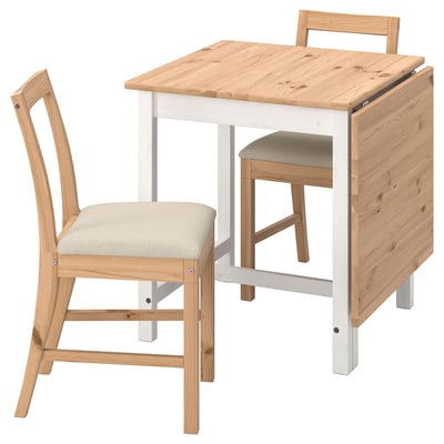 Wooden drop-leaf table with two chairs. Natural wood top, white legs. Beige cushioned seats. Minimalist design.