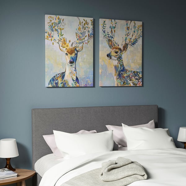 Blue bedroom with canvas deer prints above white bed linens.