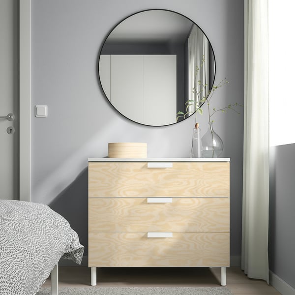 Minimalist bedroom with PLATSA chest, mirror, and plant.