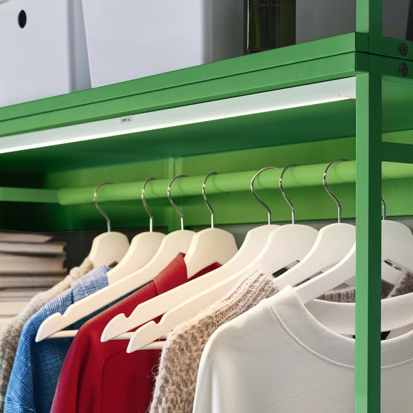 Green PLATSA rack with colourful clothes on beige hangers, led lit.